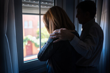 Man comforting his wife with depression and sadness and with his hand on her shoulder.