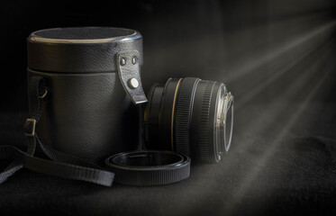 DLSR camera lens with case on a black vintage retro background
