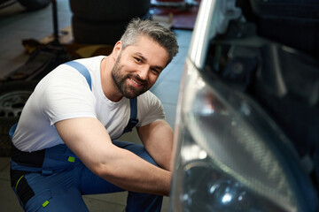 Fototapeta na wymiar Smiling pleased mechanic repairing his customer automobile