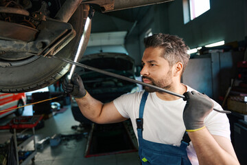 Experienced automotive service technician carrying out vehicle inspection