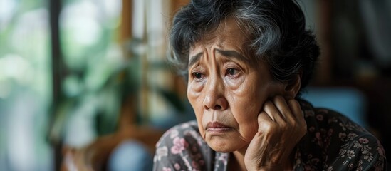 Bored elderly Asian woman deprived of companionship. - obrazy, fototapety, plakaty