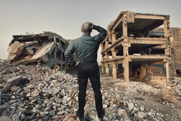 Businessman looking at destroyed residential areas