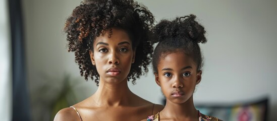 Skeptical and disapproving expression on the face of a cautious African American mother and daughter in sexy party dresses. - obrazy, fototapety, plakaty