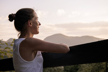 Young woman in a white tank top enjoys a beautiful natural landscape with mountain views
