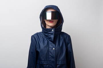 Young woman in virtual reality glasses, in a blue jacket on a light background