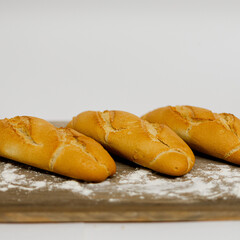Tres Mini Baguettes sobre una mesa de madera y un fondo liso blanco. 