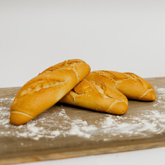Tres Mini Baguettes sobre una mesa de madera y un fondo liso blanco. 