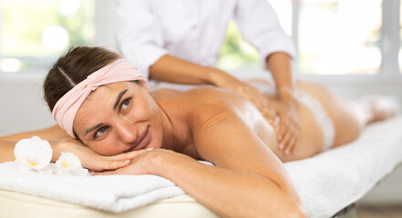Female masseuse giving back and shoulder massage to adult woman client
