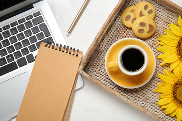 Cup of coffee, laptop, notebook and cookies on light background
