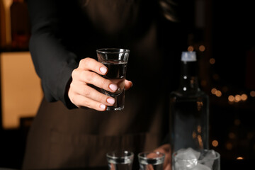 Female bartender with shot of cold vodka in bar, closeup
