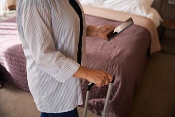 Female tourist with cellular phone and luggage in hotel room