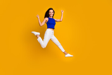 Fototapeta na wymiar Full length photo of excited lucky woman wear blue top jumping high empty space isolated yellow color background