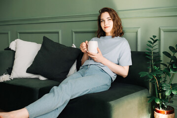 Relaxed Young Woman Reflecting with Tea/Coffee in Home Setting. Serene Mood and Introspection in...