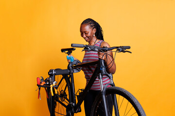 Athletic african american woman doing annual maintenance on bicycle while using professional tools. Young sports-loving female carrying damaged bike for adjustment on repair-stand.