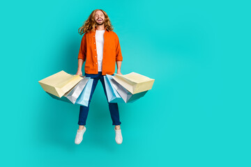 Full body length photo of young energetic funny man shopaholic jumping with pile shopping packages isolated on aquamarine color background - obrazy, fototapety, plakaty