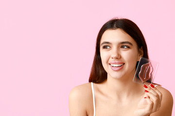 Happy young woman with lip mask on pink background