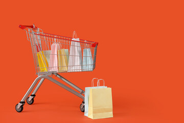 Shopping bags in cart on orange background