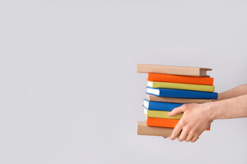 Hands holding stack of books on grey background