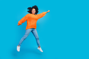 Fototapeta na wymiar Full length photo of lovely young lady jumping flying have fun wear trendy knitwear orange garment isolated on blue color background