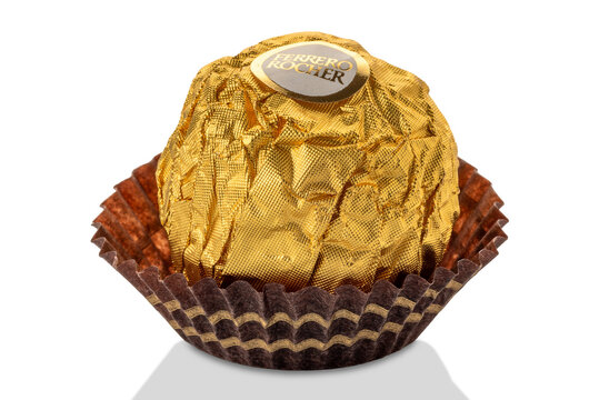 Alba, Italy - January 04, 2024: Ferrero Rocher chocolate with hazelnut filling with chocolate cream covered with hazelnut crumbs packed with golden paper, closeup with clipping path