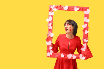 Beautiful young woman with creative makeup for Valentines Day and frame on yellow background