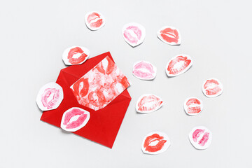 Red envelope with card and lipstick kiss marks on grey background. Valentine's Day celebration