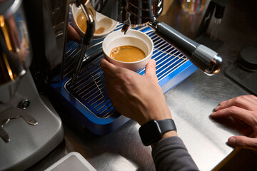 Fototapeta na wymiar Barista pouring espresso using coffee machine for brewing hot beverage