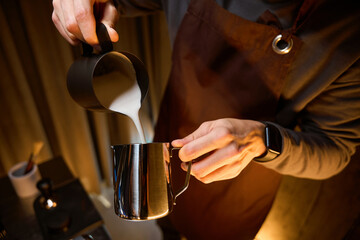 Coffee maker or bartender pouring milk from pitcher preparing coffee