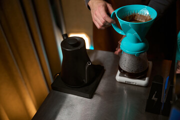 Unrecognizable barista preparing black coffee in filter and weighing for ideal proportion