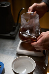 Barista pouring hot aromatic Americano from stove top coffee maker in glass cup