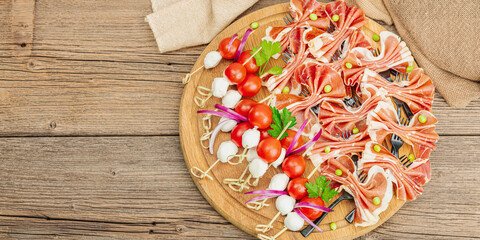 Set of picnic snacks on skewers. Jamon, mozzarella, cherry tomatoes, peas, fresh greens