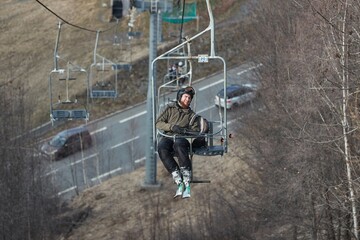 Man on ski lift at a ski resort with lack of snow