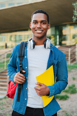 Vertical individual portrait of a african american student young man carrying a backpack and note...