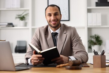 Smiling lawyer with book at table in office