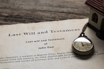 Last Will and Testament with pocket watch and house model on wooden table, closeup