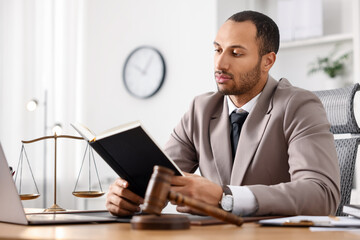 Serious lawyer reading book at table in office