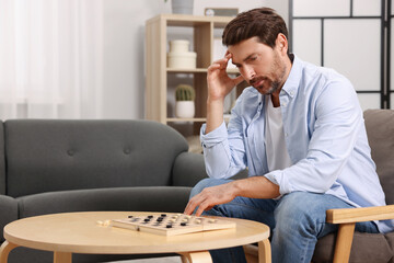 Thoughtful man playing checkers at home. Space for text