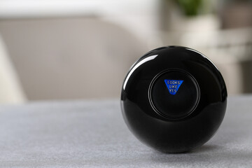 Magic eight ball with prediction Looks Like Yes on light gray table, closeup. Space for text