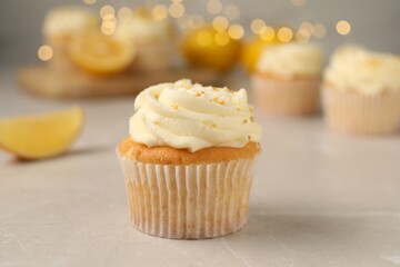 Tasty cupcake with cream and lemon zest on light table, closeup