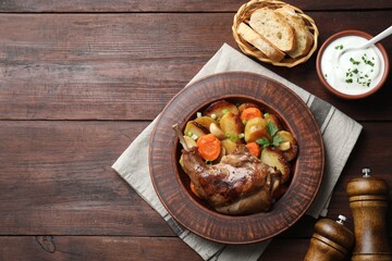 Tasty cooked rabbit meat with vegetables served on wooden table, flat lay. Space for text