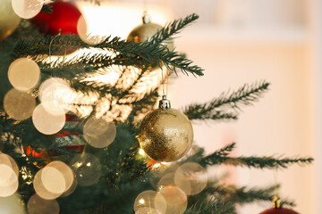 Christmas tree decorated with festive balls on light background, closeup