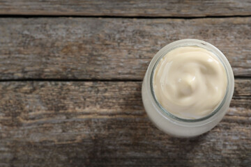 Fresh mayonnaise sauce in glass jar on wooden table, top view. Space for text