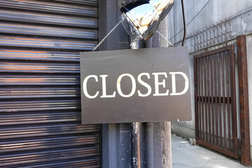 Close up of a closed sign hanging in front of the store.