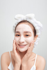 Beautiful Asian woman with facial mask on color banner background