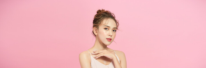 Beautiful young asian woman with clean fresh skin on pink background,