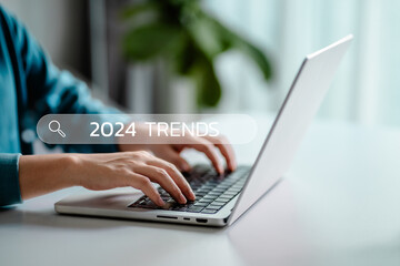 Businesswomen typing the keyword 2024 trends search in engine bar wording for marketing monitor and...