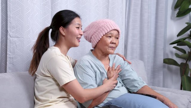 Asian caregiver nurse female takes care elderly patient woman during a chemotherapy cancer session, senior sickness retired mother and daughter worried stress and pain with negative symptoms occurred