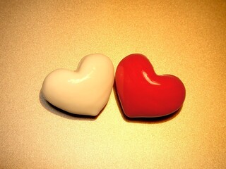 Red and White three-dimensional glossy heart to snuggle up on the golden paper..