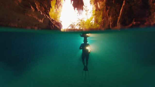 Freediver swims in the cave with torch