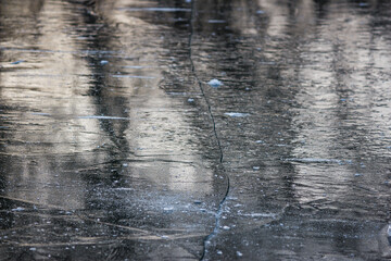 Large crack on gray ice in the middle of a pond